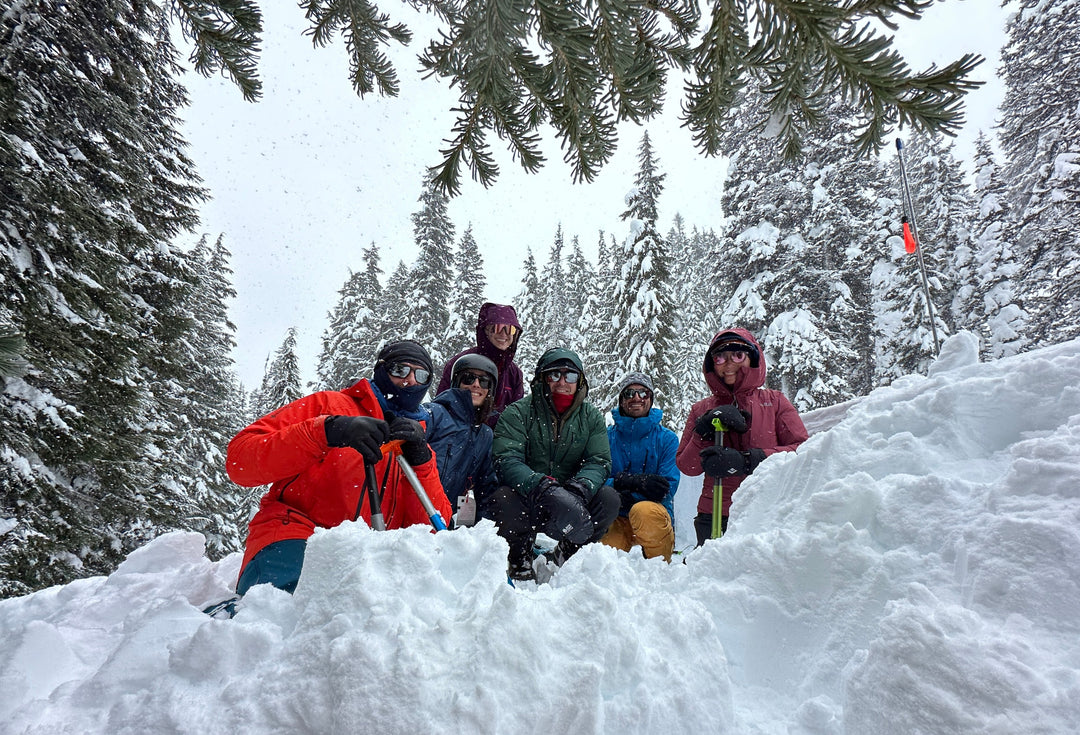 A group of avalanche course participants smiles for the camera with their shovels.