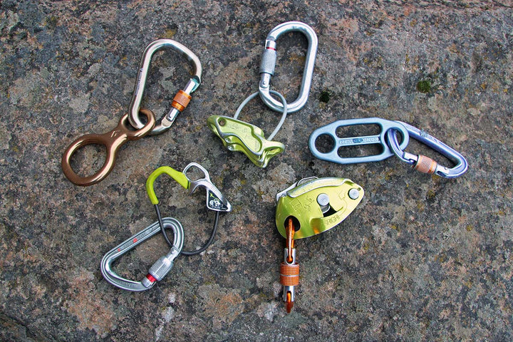 five belay devices laid out on a rock