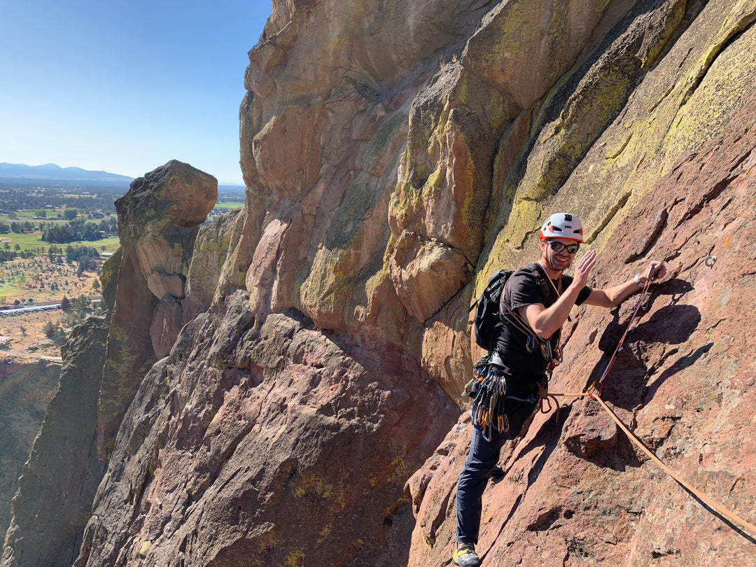 A climber waves while on the pitch 3 traverse of Dirty Pinkos, a popular 5 pitch route at Smith Rock State Park.