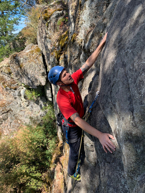 Man in red shirt and blue helmet sport climbing outdoors