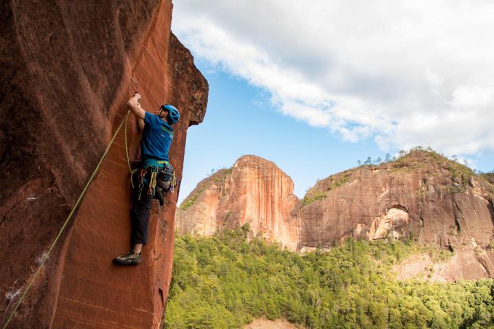 a rock climber climbs a steep sport climbing route in Liming, Yunnan, China